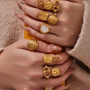 Detail shot of vintage matte gold geometric rings with shell inlay on female model hand
