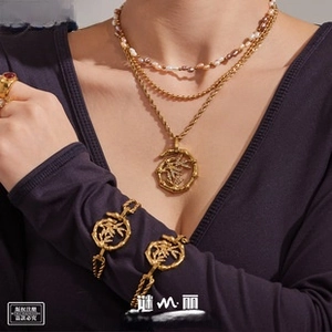 Detail view of gold tiered pearl necklace and bamboo textured bracelets on model