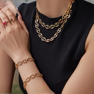 Close-up of gold-plated anchor chain necklace and bracelet with red gemstone ring