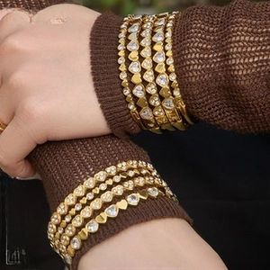 Detail of gold-plated heart-shaped bracelet with embedded crystals on female wrist