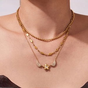 Detailed view of triple-layered gold-plated necklace with star and wings pendant