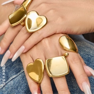 Close-up of gold plated titanium steel heart and geometric rings on a model's hand