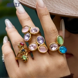 Close-up of stacked gold-plated titanium rings with colorful gemstone inlay details