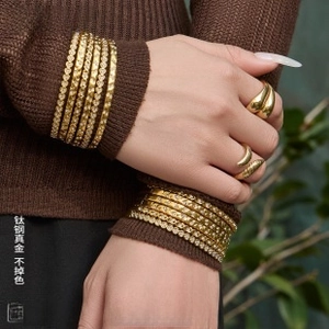 Detail of 18K gold plated titanium steel bangles and rings on a female model