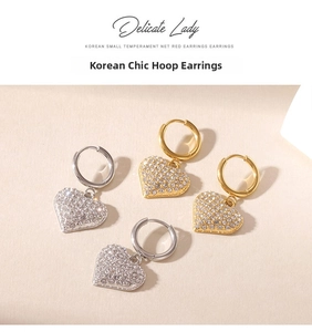 Detailed view of gold and silver heart drop earrings with shimmering white rhinestones