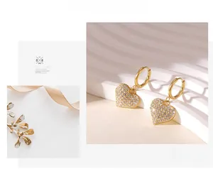 Detail shot of heart-shaped gold earrings encrusted with sparkling zircon stones