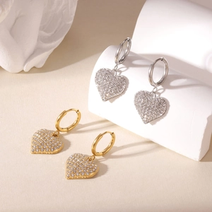 Elegant gold and silver heart hoop earrings with sparkling zircon crystals on white stone