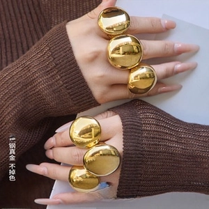 Close-up of polished gold-plated stainless steel teardrop rings worn by a model