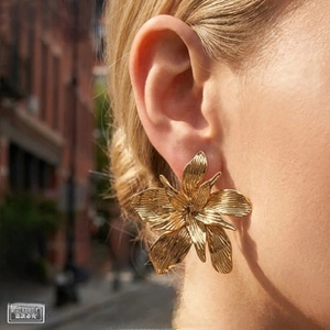 Macro shot of 18k gold plated titanium steel flower earrings worn by a model