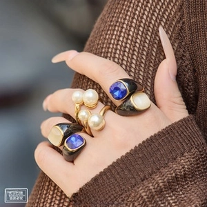 Close-up of titanium steel gold plated rings with black shells and blue square gemstones