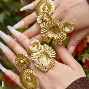 Detail of oversized 18k gold plated pleated flower rings on hand in natural light