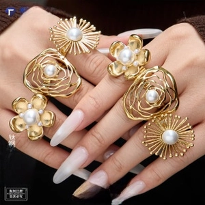 Macro detail of gold-plated stainless steel daisy pearl rings set on a model hand