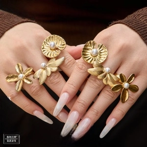 Detail of adjustable gold-plated leaf and flower rings with pearls on fingers