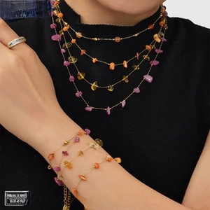 Detail of bohemian gold-plated layered necklace with purple and orange gemstone beads