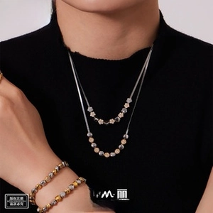 Detailed view of layered stainless steel star necklaces and bracelets with gold and silver beads