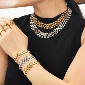Detail showing stacked punk style stud necklaces and bracelets in gold and silver finish