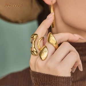 Close-up of golden irregular fluid-shaped rings made of premium titanium steel on a finger