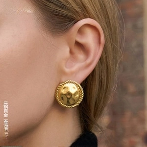 Detail of 18k gold plated titanium steel earrings with hammered texture and twisted edges