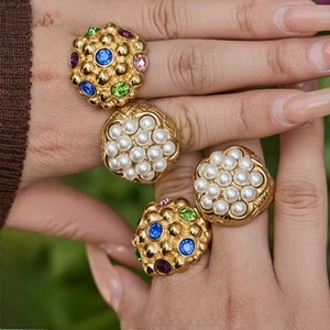 Macro detail of vintage gold plated rings with colorful rhinestones and faux pearls