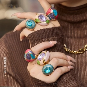 Detail of 18K gold plated interlocking rings with colorful crystals and enamel on hands