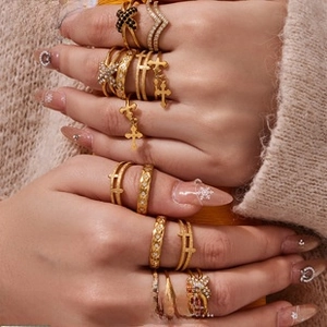 Close-up of a model wearing stacked 18K gold-plated braided rings with cross charms