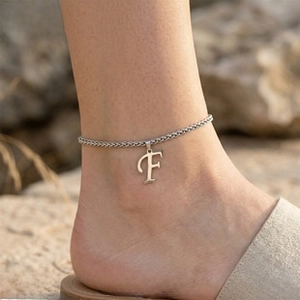 Silver ankle chain featuring a bold letter F pendant shown on a model at the beach