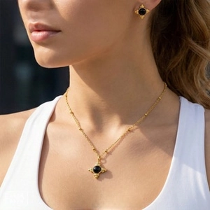 Detailed view of 18K gold plated vintage cross necklace and earring set with black stone