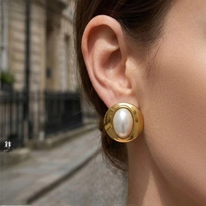Close-up of model wearing gold-plated titanium pearl earring on a scenic street