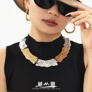 Detail of mixed-metal wavy textured necklace with gold and silver plates on model