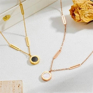 Macro detail of gold and rose gold necklaces with Roman numeral engraved pendants