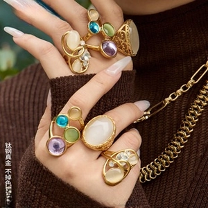 Close-up of gold titanium steel rings with colorful oval gemstones and thick chain necklace