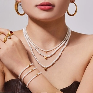 Three-layer pearl necklace with matching bracelet and gold rings set on model