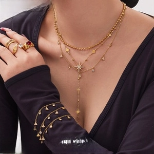 Macro shot of layered gold star necklaces and red heart ring worn by model