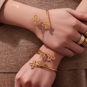 Detail of 18K gold clover bangle bracelets with beaded texture worn on model's wrist