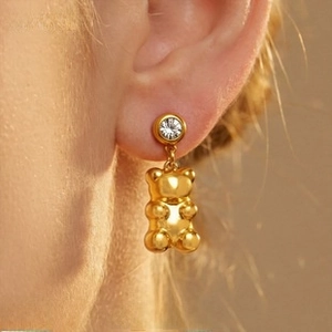 Detail of 18K gold-plated C-shaped bear earring with crystal stud worn on the ear