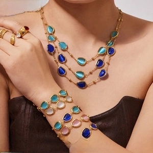 Detail of layered gold-plated necklaces and beaded bracelets with colorful gemstones