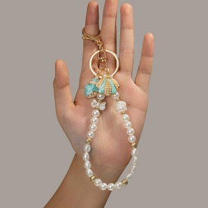 Detail of beaded keychain with sea shells, faux pearls and golden crown charms