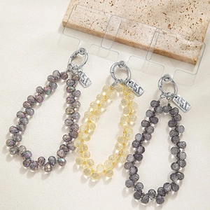 Macro detail of faceted crystal phone lanyards with silver spring hooks on stone tray