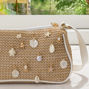 Close-up of a straw shoulder bag featuring sea shell, starfish and turtle metal charms