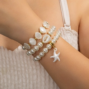 Close-up of bohemian layered bracelets set featuring white sea shells and starfish charms
