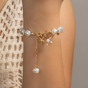 Close-up of baroque pearl bracelet with gold starfish charms and rhinestone details