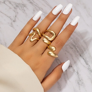 Close-up of three matte gold irregular geometric rings on hand with marble background