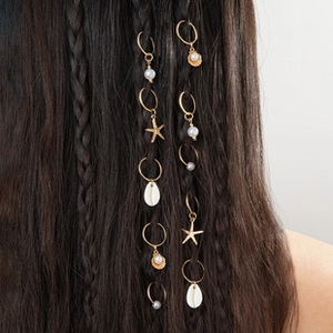 Detail of bohemian gold hair rings with starfish shells and pearls in braided hair