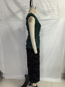 Dettaglio dell'abito con paillettes verde scuro e nero con texture riflettente e lucida