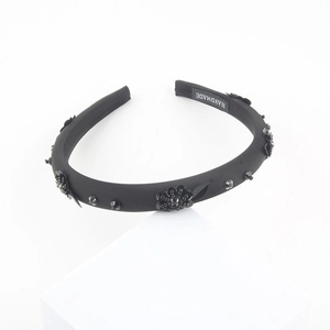Detail of handmade black headband with beadwork flowers and white woven handmade label