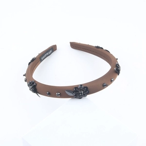 Detail of brown fabric headband with black sequin flowers and a handmade label
