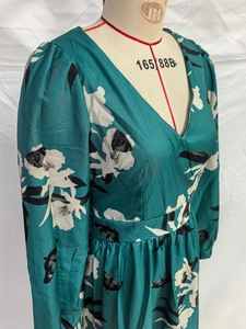 Détail de robe fleurie verte avec col en V et manches bouffantes sur un mannequin