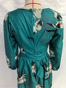 Détail de la robe d'hiver à col en V avec imprimé floral vert foncé et manches lanterne