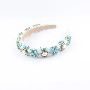 Close-up of luxury sponge headband with blue crystals and white pearls on blue fabric