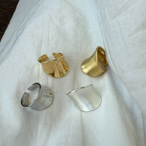 Detail of irregular C-shaped open rings in gold and silver with matte brushed finish